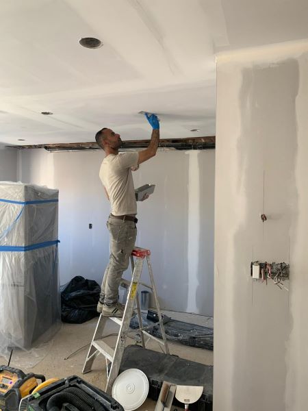 A construction worker installing drywall with precision.